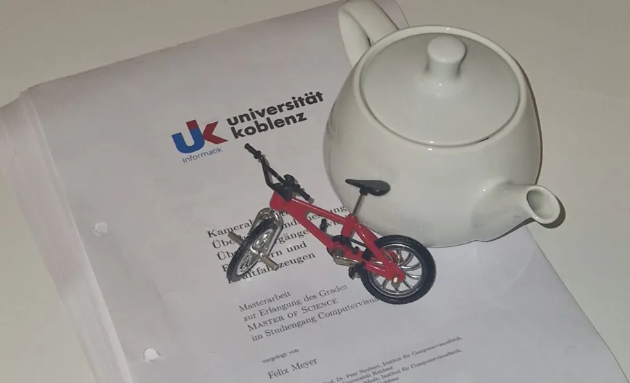 die ausgedruckte Masterarbeit, darauf: ein Utah Teapot und ein kleines Fahrradmodell