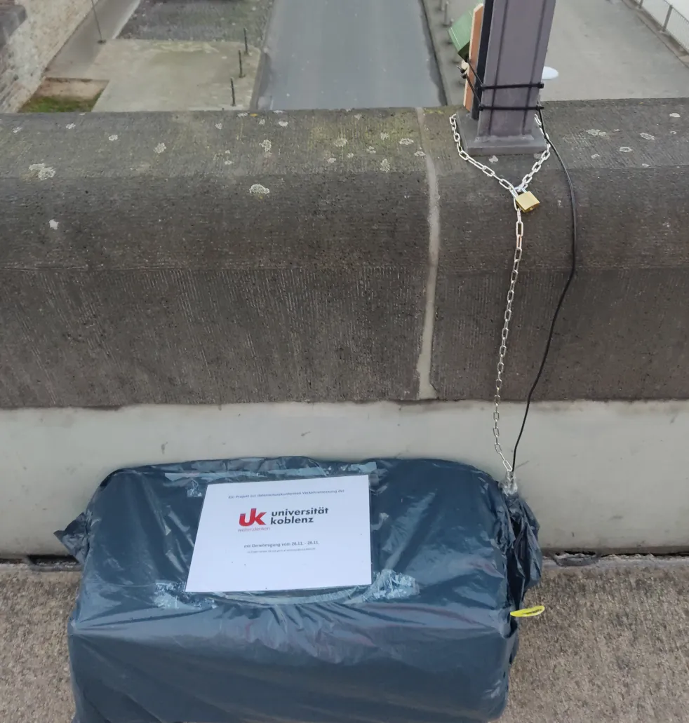 in wetterdichter Folie eingepackter Prototyp. Mit einem Kabel verbunden: durch ein Vogelhäuschen vor Wetter geschützte Kamera.